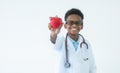 Selective focus on hand holding heart, little cute African Nigerian boy doctor wear medical uniform glasses with stethoscope, Royalty Free Stock Photo