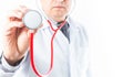 Selective focus of a hand holding a red stethoscope, with a doctor in a white coat and tie out of focus on white background Royalty Free Stock Photo