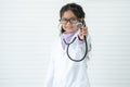 Selective focus on hand of little cute Asian child girl doctor in medical uniform and glasses, holding stethoscope playing doctor Royalty Free Stock Photo