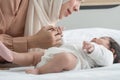 Selective focus on hand of Muslim newborn baby 1 month old grabbing young mother finger wearing hijab, lying on bed with cute