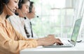 Selective focus on hand of young operator woman typing and working with headset smiling and doing customer support at work Royalty Free Stock Photo