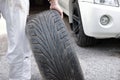 Selective focus on hands of automotive mechanic in uniform holding tire for fixing car at the repair garage background.