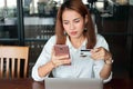 Selective focus on hands of young Asian woman holding credit card and mobile smart phone in living room. Online shopping concept. Royalty Free Stock Photo