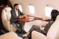 selective focus of handsome bearded businessman holding gadget while sitting with businesswoman in private jet. Royalty Free Stock Photo
