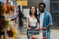 Focus of happy asian woman and cheerful african american man looking at shelves in supermarket Royalty Free Stock Photo