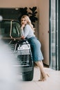 Selective focus of happy blonde girl standing near black automobile in car showroom.