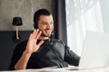 Focus of happy operator in headset waving hand while having video call at home