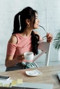 Focus of happy young asian woman holding gasses near lips and cup of tea