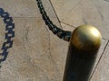 Heavy brass chain of square links with strong shadow and blurry post