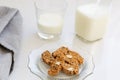 Almond and chocolate biscotti in vintage scalloped glass plate, with grey serviette and bottle and small glass of milk