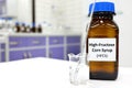 Selective focus of high-fructose corn syrup or hfcs food and beverage sweetener in dark brown glass bottle inside a laboratory.