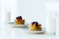 selective focus of homemade pancakes with berries and honey and glasses of milk on tabletop