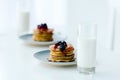 selective focus of homemade pancakes with berries and honey and glasses of milk