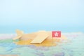 Selective focus of Hong Kong flag in blurry world map and wooden airplane model. Hong Kong as travel and tourism destination