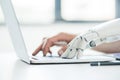 selective focus of human and robot hands typing on laptop