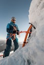 selective focus on ice axe and man climber with equipment and ropes on the slope Royalty Free Stock Photo