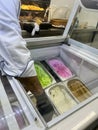 Selective focus on ice cream in trays and seller`s hands behind glass. Ice cream in different flavors