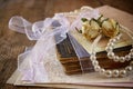 Selective focus image of dry roses, white pearls necklace and old vintage books on wooden table. retro filtered image Royalty Free Stock Photo