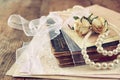 Selective focus image of dry roses, white pearls necklace and old vintage books on wooden table. retro filtered image Royalty Free Stock Photo