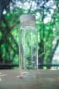 Selective focus image of empty plastic bottle with white lid, water drops in glass Royalty Free Stock Photo