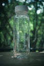 Selective focus image of empty plastic bottle with white lid, water drops in glass Royalty Free Stock Photo