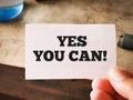 Selective focus image with noise effect hand holding white card with text YES YOU CAN. Royalty Free Stock Photo