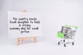 Selective focus image of trolley cart and bank note with economy quote on a white board. Economy concept