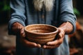 Selective focus on impoverished old mans hands clutching an empty bowl