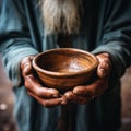 Selective focus on impoverished old mans hands clutching an empty bowl