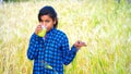 Selective focus on Indian girl taking orange fruit juice in his field and seeing at camera. Girl in agriculture field with orange Royalty Free Stock Photo