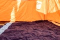 Selective focus of an inflatable air mattress on the floor of a tent being filled up.