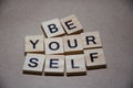 Selective focus on Inscription Be Yourself outlined on beige background with copy space. Motivational card with phrase be yourself