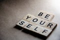 Selective focus on Inscription Be Yourself outlined on beige background with copy space. Motivational card with phrase be yourself