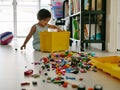Selective focus of interlocking blocks being poured and spread out on the floor by little Asian baby girl sitting in the backgroun