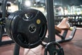 Selective focus at the iron weight plate attached to barbell on the floor inside of fitness gym with blurred background of weight Royalty Free Stock Photo