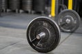 Selective focus at the iron weight plate attached to barbell on the floor inside of fitness gym with blurred background of weight Royalty Free Stock Photo
