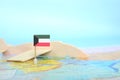 Selective focus of Kuwait flag in blurry world map and wooden airplane model. Kuwait as travel and tourism destination concept.