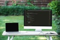 selective focus of laptop with blank screen and computer with programming language code at table