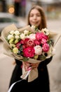 Selective focus of large luxurious flowers bouquet with protea, roses, peonies, eucaluptys wrapped in craft paper in