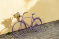 selective focus on lavender bicycle with flowers on yellow wall background Royalty Free Stock Photo