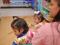 Little Asian baby girl  furthest  looking and standing in a shopping cart with her sister while her mother Royalty Free Stock Photo