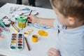 selective focus of little boy with brush and paintings drawing picture alone