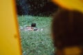 Selective focus of little girl sitting in tent and looking at warm calm campfire near forest in evening summertime. Hiking,