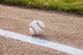 Selective focus low angle view of a baseball on gravel infield near stripe and grass