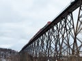 Freight train on 1908 railway trestle bridge seen from during a cloudy winter morning