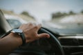 Selective focus of a luxury and elegant wristwatch on a man's hand driving a car