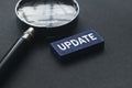 Selective focus of magnifying glass and blue wooden cube written with Update