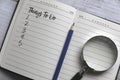 Selective focus of magnifying glass,pencil and notebook written with list of numbers of things to do