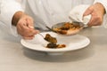 Selective focus of a male chef arranging a plate of beef stew with a spoon on a table Royalty Free Stock Photo