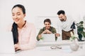 Selective focus of male coworkers looking at laptop and smiling